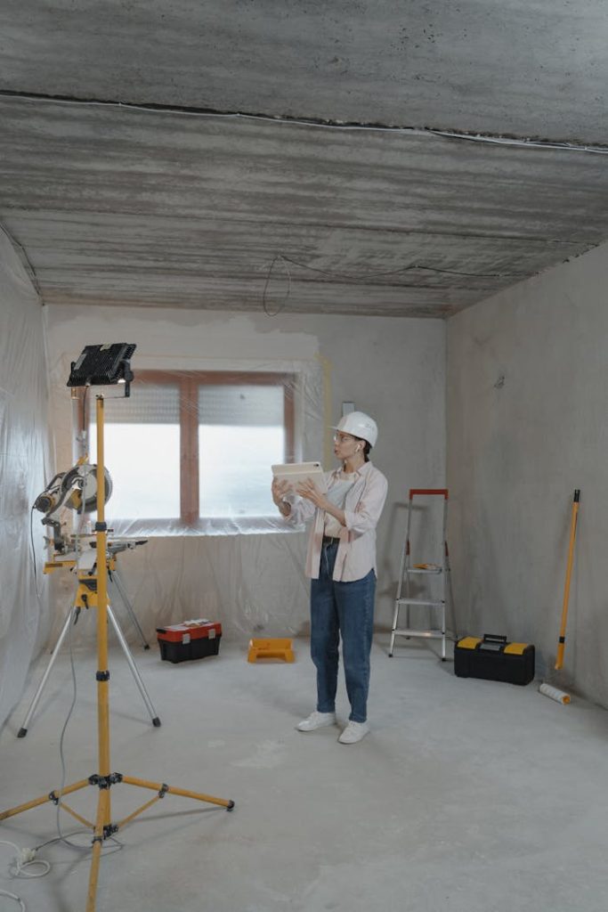 woman-holding-an-ipad-6474507 Woman with hard hat and tablet assessing a residential renovation site.